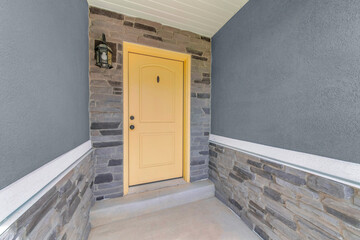 Exterior of an entrance of a house with yellow front door and gray sidings