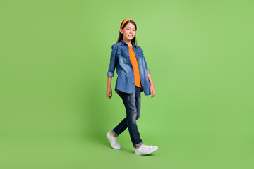 Full length photo of cute small girl go wear hoop shirt jeans sneakers isolated on green background