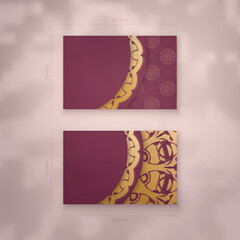 Burgundy business card template with abstract gold pattern for your business.