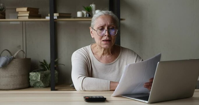 Worried anxious mature woman pensioner count payments before pc screen find unexpected debt overdue fee. Nervous stressed older female having financial problem unable to pay too high utility charges