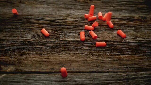 Ear plugs falling down on rustic wood in slow motion