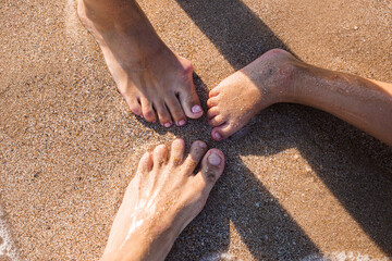 Men's, women's and children's bare feet on a sandy beach. Top view, flat lay