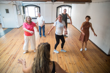 Group of seniors learning twist dance steps. Caucasian retirees twisting in studio. Dance, hobby, healthy lifestyle concept