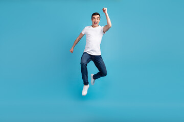 Fototapeta na wymiar Full length photo of young cheerful guy go walk run jump up hurry fast isolated over blue color background