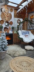 Wnętrze zimowego domku w stylu boho, wiszący kokon przy ciepłym kominku © Beenis