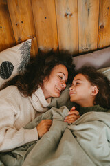 Happy young woman with cute teenage daughter posing in bed.