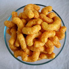 nut flips. lots of corn sticks in peanut glaze in a glass round bowl on a gray  background. top view
