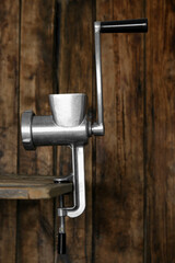 Metal manual meat grinder on table against wooden background