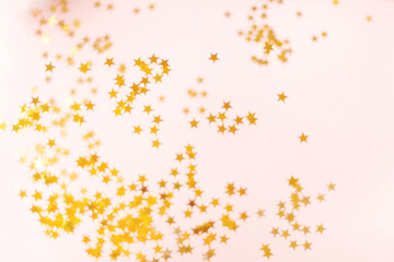 A beautiful blur of the glitter of gold stars on a pink background. Confetti abstraction and sequins for beautiful background design