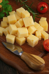 Close-up shot of cheese slices with knife on rustic wooden table