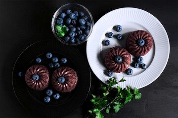Obraz na płótnie Canvas Black and white plates with blueberry muffins. Decorations from a living decorative branch. View from above.
