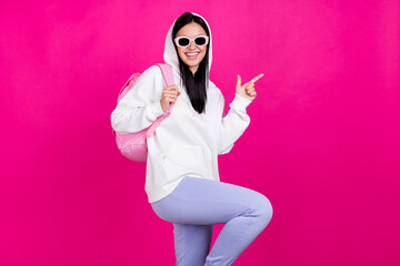 Photo of confident student lady direct finger empty space wear bag white sweatshirt isolated pink...