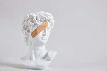 bust of an antique king with a medical adhesive plaster on his face