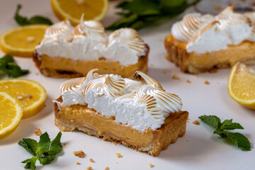 Lemon cake with protein cream, on a light background, with lemon slices and mint leaves.
