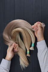 Man holding in hands different types of hair.Top view of the different hairs sections.Hair extensions concept. © Bidzilya