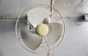 An old electric fan which installed on the ceiling of room, selective and soft focus.