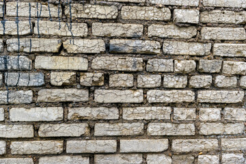 Old brick wall for a backdrop. Gray bricks. Trickles of black paint, cracks, stones.