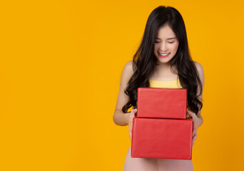 Fototapeta na wymiar Happy young lady look at red gift box or New year gift box or Christmas present box with smile face and happiness stand over yellow background copy space Christmas day Birthday and New year concept