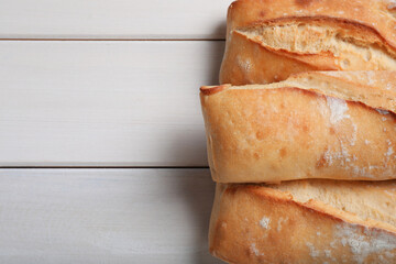 Tasty baguettes on white wooden table, flat lay. Space for text