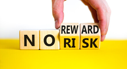 No risk or reward symbol. Businessman turns wooden cubes and changes words 'no risk' to 'no...