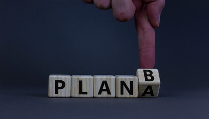 Plan A or B symbol. Businessman turns a wooden cube and changes words Plan A to Plan B. Beautiful grey table, grey background, copy space. Business and Plan A or B planning concept.