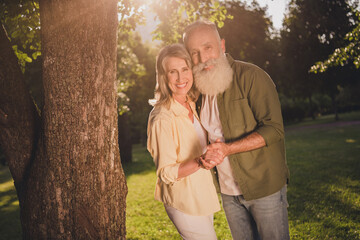 Photo of cheerful couple husband wife spouses embrace outdoors romance hold hands trees nature outdoors