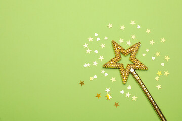 Beautiful golden magic wand and confetti on light green background, flat lay. Space for text