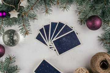 Tarot cards fanned back up on white concrete surface with Christmas tree branches and decor. Minsk, Belarus, 19.11.2021