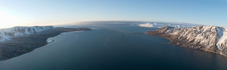Panorama of coastal mountains of Chukotski peninsula covered with snow. In solar weather.