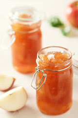 Apple jam in a glass jar. Apple jam on a light background. Delicious natural marmalade.