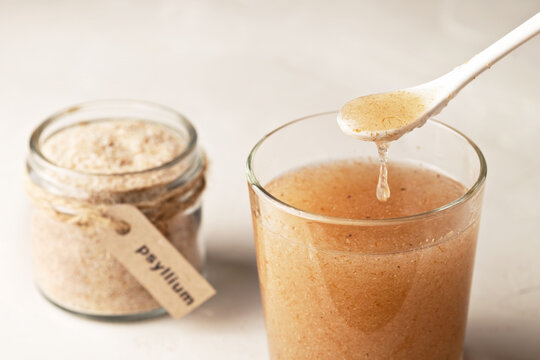 Plantain husk in a jar with the inscription psyllium and a glass of water on a light background.