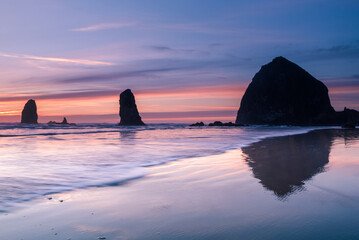 Fototapeta na wymiar Waves in front of Cannon beach haystack at sunset