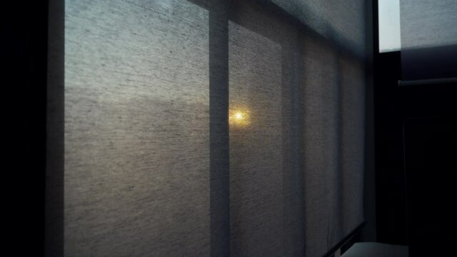 Sun shines through the closed blinds on the window, opening closing roller blind curtain on a frozen balcony window. High quality 4k footage
