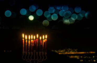 Festive menorah and burning wax candles as symbol of Hanukkah - Jewish Holiday of Miracle Light, blurred digitally generated bright bokeh