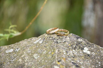 Argollas o anillos de boda encima de una piedra con fondo verde desenfocado