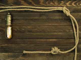 Wooden background made of dark brown boards with a glowing specular bulb and hemp ropes. Deck texture.