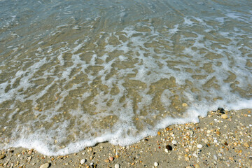 Cape May surf washing up in small waves over shells and pebbles on the shoreline
