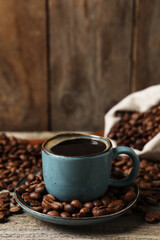 Cup of aromatic coffee and beans on wooden table