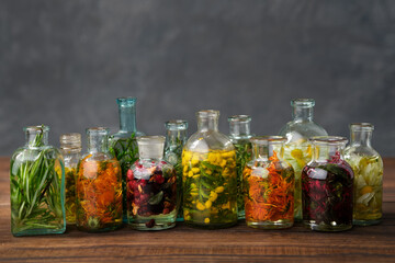 Bottles of essential oil or infusion of medicinal herbs and berries - rosemary, calendula, tansy, thuja, thyme, bergamot, chamomile.  Healing plants, medicinal herbs and berries. Alternative medicine. - obrazy, fototapety, plakaty