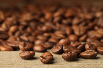 Many roasted coffee beans on wooden table, closeup