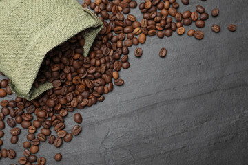 Bag with roasted coffee beans on black table, flat lay. Space for text