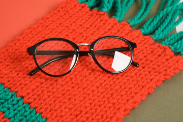 stylish glasses on red knitted scarf, christmas concept