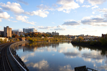 wide angle urban landscape view of the Harlem River as it curves around into the East River, North Bronx with fall foliage in the distance, beautiful twilight clouds reflected on the water