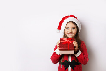 Happy child girl in Christmas hat holding red gift box isolated on white background