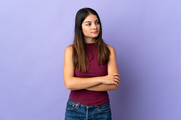 Young caucasian woman isolated on purple background looking to the side