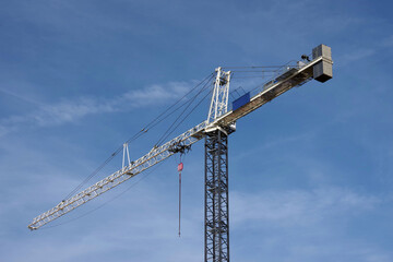 Tall construction crane under blue sky with clouds