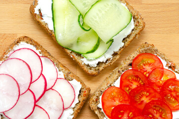 Vegetarian sandwiches with cream cheese, fresh cucumber, radish, tomatoes on a cutting wooden board on a concrete background. Flat lay. healthy food diet slimming fitness. close-up.