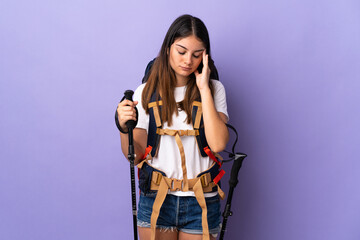 Young woman with backpack and trekking poles isolated on purple background with headache
