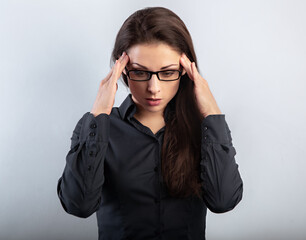 Beautiful serious unhappy concentrated thinking young woman in eyeglasses solving the problem on empty blue studio copy space. Closeup