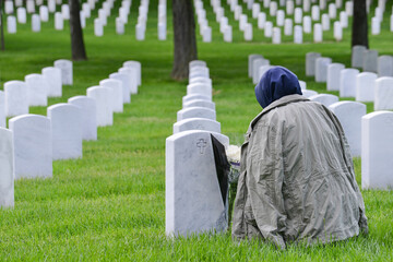 A woman with a khaki military jacket mourns in Arlington National Cemetery - Circa Washington D.C....